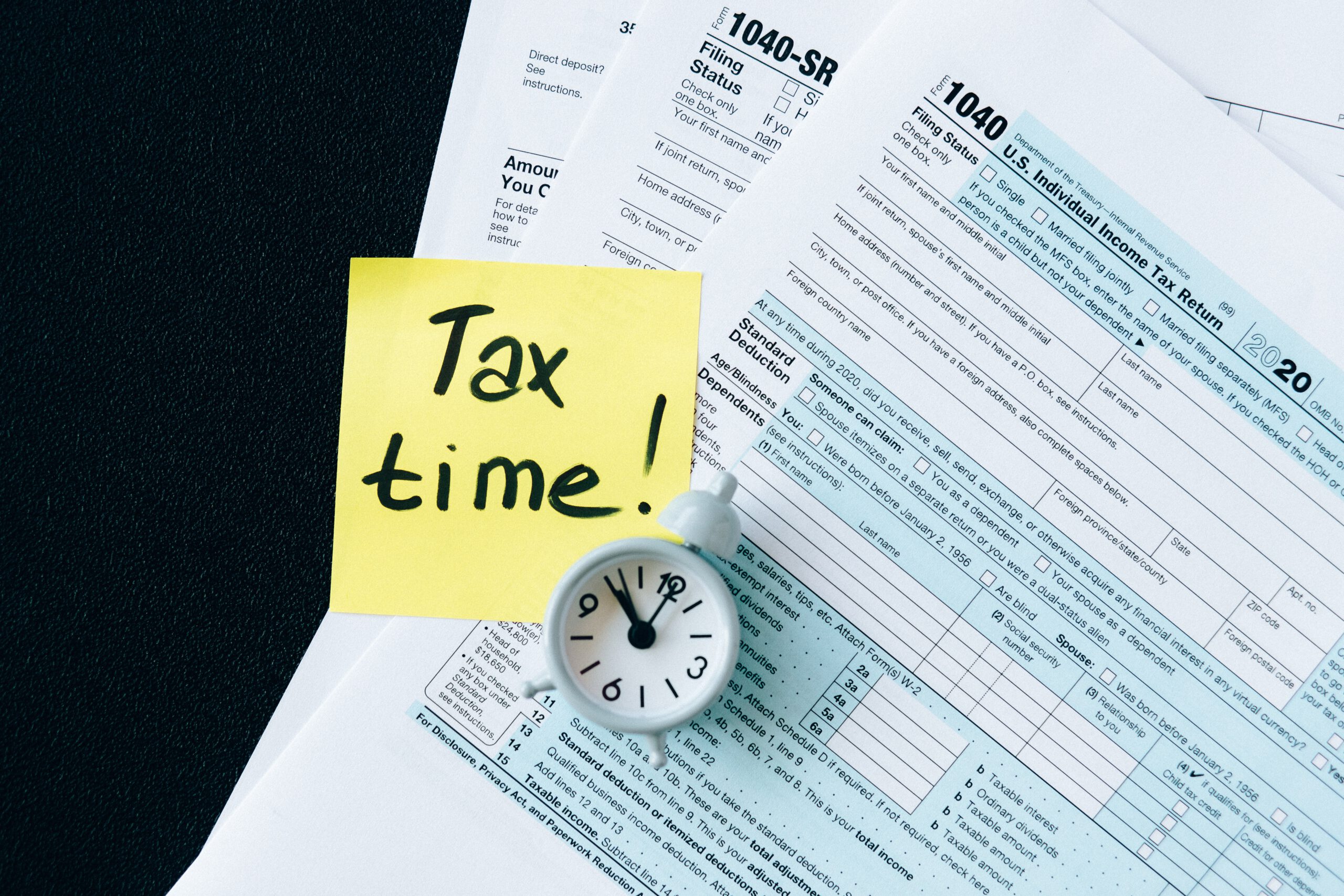 Karteczka z napisem tax time leżąca na pliku dokumentów podatkowych